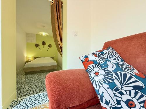 une chambre avec un lit et un canapé avec un oreiller dans l'établissement L'Entre-Rives, à Rochefort