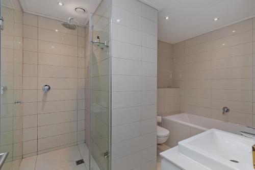 Un baño con ducha, lavabo e inodoro. en Stay In Luxury at The Pullman, en Ciudad del Cabo