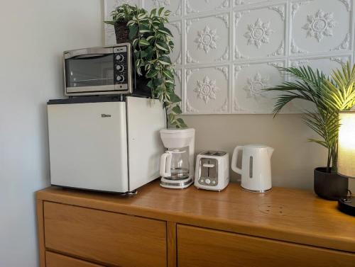 a microwave on top of a refrigerator on a wooden cabinet at Studio 10 - 2 min du Bord de l'eau Foyer & Barbecue in Sainte-Anne-de-Beaupré