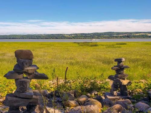 two stone statues sitting on top of a field at Studio 10 - 2 min du Bord de l'eau Foyer & Barbecue in Sainte-Anne-de-Beaupré