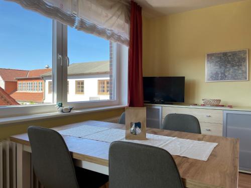 a dining room table with chairs and a large window at Altstadtwohnung 2, Süderstraße in Wyk auf Föhr