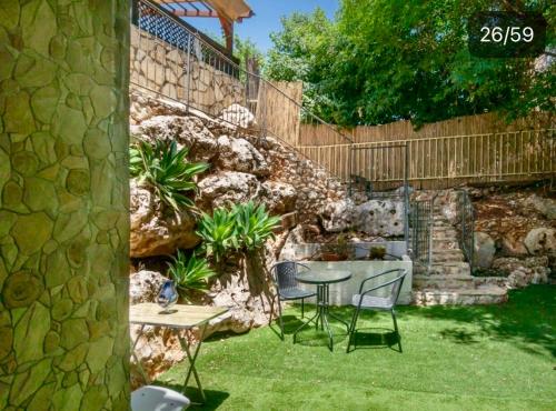 a garden with a table and chairs and a stone wall at Panorama Kinneret נוף כנרת, צפת in Safed