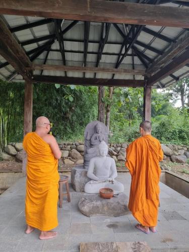 two men in orange robes standing in front of a statue at Puunee Wild River Villa's Borobudur in Borobudur