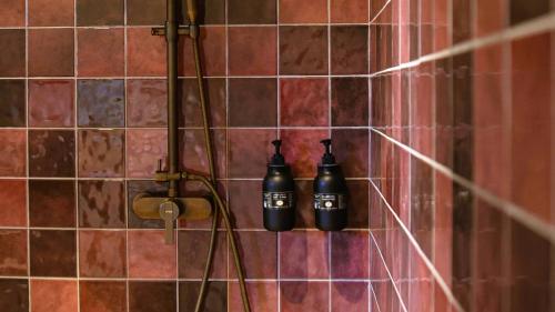 deux bouteilles noires sur un mur carrelé dans une douche dans l'établissement Domaine de Gialla Bergerie Quercia, 2 pers, piscine chauffée, 10 mn plage, à Arraggio