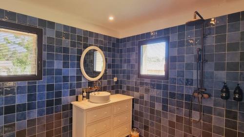 La salle de bains est pourvue de carrelage bleu, d'un lavabo et d'un miroir. dans l'établissement Domaine de Gialla Bergerie Figa, 4 pers, piscine chauffée, 10 mn plage, à Arraggio