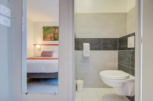 a bathroom with a toilet and a bed in a room at Hôtel Saint Louis in Le Thor