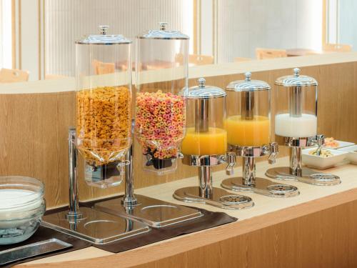 a counter with three vases of food and orange juice at Le Collective Gangnam SAC Roium in Seoul