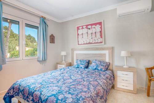 Un dormitorio con una cama con edredón azul y dos ventanas. en Villa Sophie, en Denia