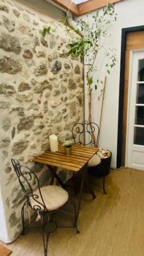 une table et des chaises dans une pièce avec un mur en pierre dans l'établissement Le Patio du bien-être, à Béziers