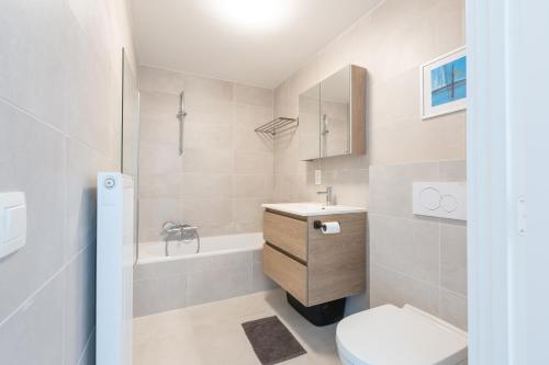 a bathroom with a toilet and a sink and a tub at LECOMTE - The Shoreline Green 153 in Ostend