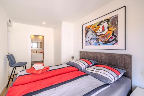 Una cama en un dormitorio con un cuadro en la pared. en Vista Castillo, en Denia