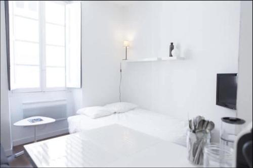 une chambre blanche avec un lit et une télévision dans l'établissement Studio hyper centre historique Quai bourgeois, à Bordeaux