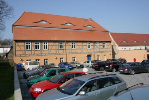a large building with cars parked in a parking lot at Pension zur Postmeile in Bad Belzig