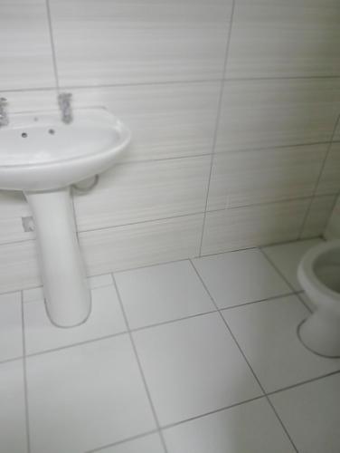 a white bathroom with a sink and a toilet at Moonlight Guesthouse - Boksburg in Boksburg