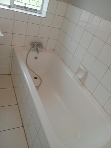 a white bath tub in a bathroom with a window at Moonlight Guesthouse - Boksburg in Boksburg