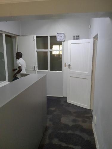 a person in a room with a counter and a door at Moonlight Guesthouse - Boksburg in Boksburg