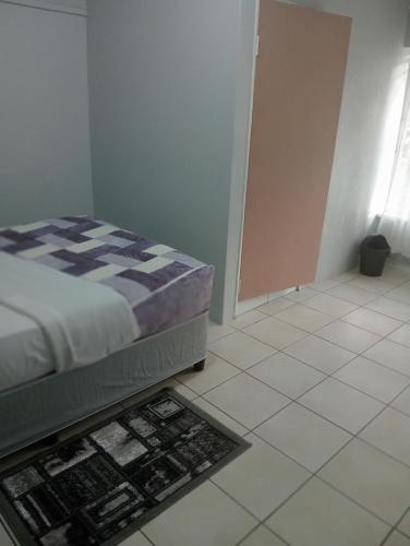 a bedroom with a bed and a tiled floor at Moonlight Guesthouse - Boksburg in Boksburg