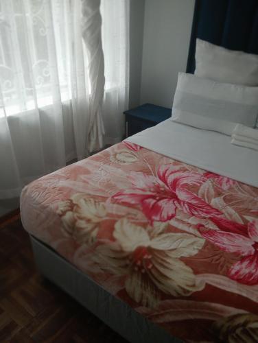 a bedroom with a bed with a flower pattern on it at Moonlight Guesthouse - Boksburg in Boksburg