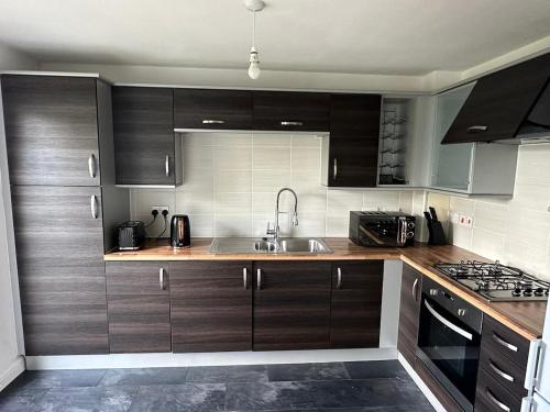 a kitchen with wooden cabinets and a sink at 2 Bed 2 Bath Flat 27Atholway in Uphall