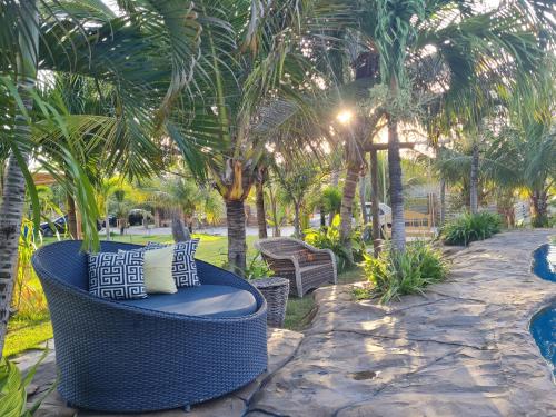 a blue wicker chair sitting on a patio with palm trees at Chalés Refúgio Fortim in Fortim
