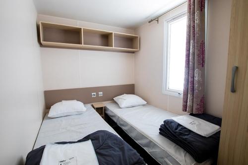 deux lits dans une petite pièce avec une fenêtre dans l'établissement Camping Domaine du Cros d'Auzon - Maeva, à Saint-Maurice-dʼArdèche