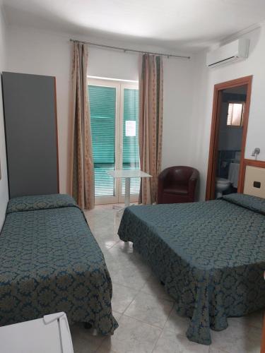 a bedroom with two beds and a chair and a window at Hotel Klein Wien in Piano di Sorrento