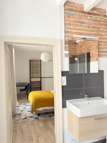 La salle de bains est pourvue d'un lavabo et d'un mur en briques. dans l'établissement Hypercentre - 2 chambres - proche commerces, à Cholet