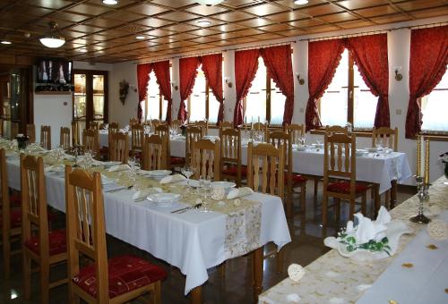 a dining room with white tables and chairs and windows at Penzión Salaš Cabaj in Nitra