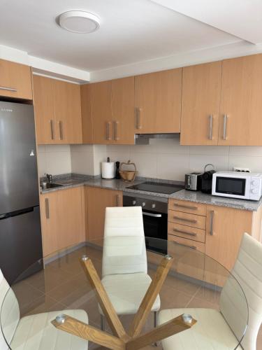 a kitchen with wooden cabinets and a table and chairs at Camino Fisterra Beach - Apartment in Fisterra