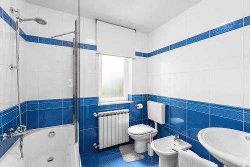 a blue and white bathroom with a toilet and a sink at Vista OLIVO in Brtonigla