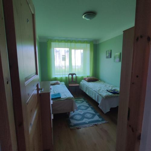 a green room with two beds and a window at Vormsi Ohvitseride Maja korter nr 3 in Hullo