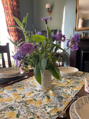 a vase filled with purple flowers on a table at The Old Rectory in Stewartstown