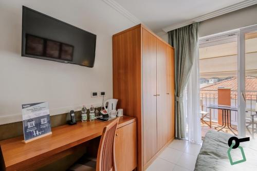 a room with a desk and a television on a wall at HOTIDAY Room Collection - Alassio Centro in Alassio