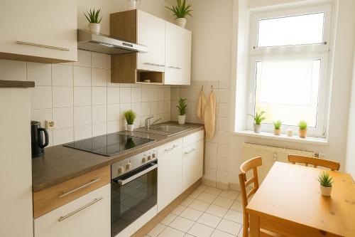 cocina con armarios blancos, mesa y fregadero en SUNNYHOME Monteurwohnungen und Apartments in Erfurt, en Erfurt