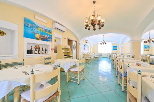 a restaurant with white tables and chairs and a chandelier at Av Club Terme Colella in Ischia