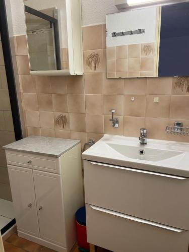 une salle de bain avec un lavabo blanc et un miroir dans l'établissement Les logis de Magali les Zodiacs, terrasse, plage à 600m, à Argelès-sur-Mer