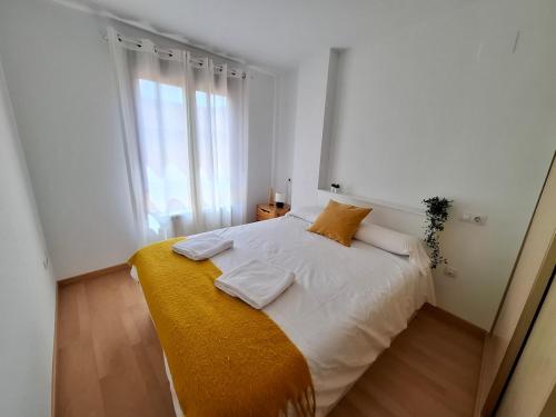 a bedroom with a white bed with a yellow blanket at Los Pinos, acogedor apartamento con garaje - Arafita Apartamentos in Sabiñánigo