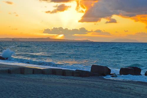a sunset on the beach with rocks in the water at Splash's Rooms in Spadafora
