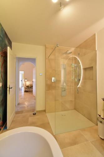 une salle de bain avec baignoire et douche en verre dans l'établissement Ferienhaus Équilibre, ideal für Familien oder Hundefreunde, toller Pool und Meerblick, à Saint-Peïre-sur-Mer