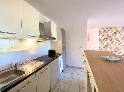 une cuisine avec un évier et un plan de travail dans l'établissement La Palmeraie T2, terrasse, clim, pkg, centre ville, à Montpellier