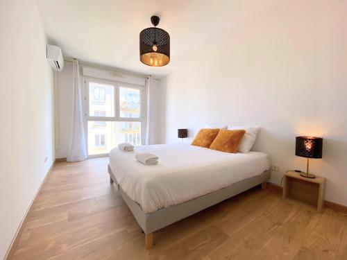 - une chambre blanche avec un lit et une lampe dans l'établissement La Palmeraie T2, terrasse, clim, pkg, centre ville, à Montpellier