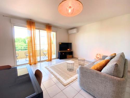un salon avec un canapé et une télévision dans l'établissement La Palmeraie T2, terrasse, clim, pkg, centre ville, à Montpellier