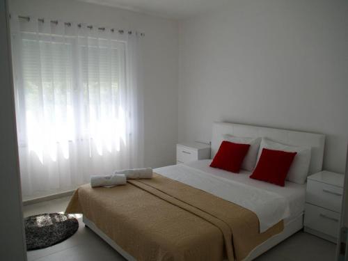 a bedroom with a bed with red pillows and a window at Sam Villa in Ulcinj