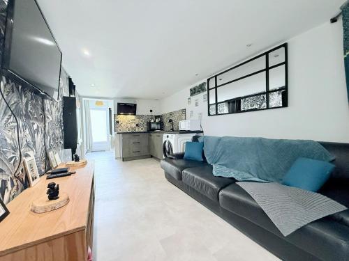 un salon avec un canapé noir et une cuisine dans l'établissement 1753-3 L'atelier secret, à Échillais