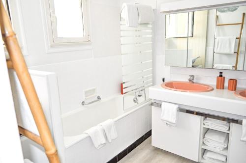 une salle de bain blanche avec un lavabo et un miroir dans l'établissement La Villa du Brittany, à La Baule
