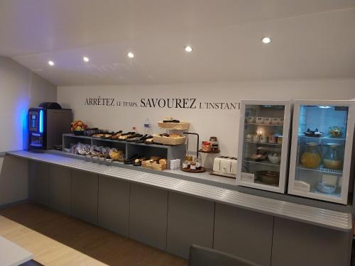 a bakery with a counter with pastries on it at Kyriad Hôtel La Fleche in La Flèche