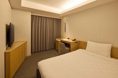 a hotel room with a bed and a television at Kobe Motomachi Tokyu REI Hotel in Kobe