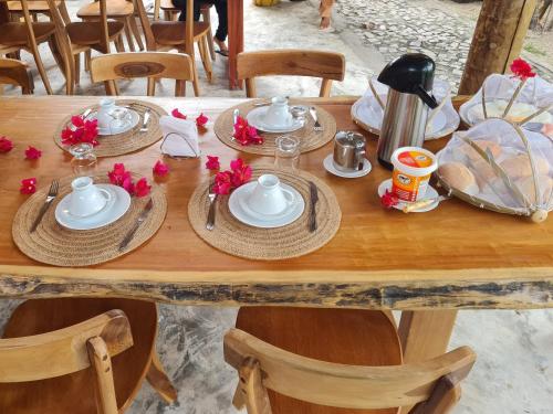 a wooden table with plates and dishes on it at Chalés Refúgio Fortim in Fortim