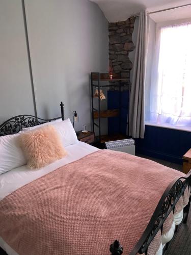 a bedroom with a bed with a pink blanket and a window at The Kings Head in Cheddar