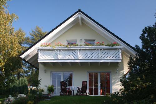 a white house with a balcony with flowers on it at Ferienhaus Vogtlandresidenz in Beerheide